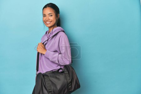 Foto de Joven Filipina con mochila deportiva para el gimnasio sobre fondo azul - Imagen libre de derechos