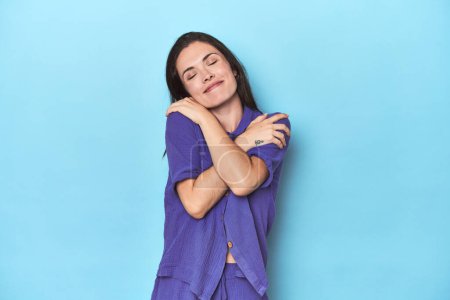 Photo for Young caucasian woman on blue backdrop hugs, smiling carefree and happy. - Royalty Free Image