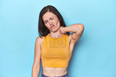 Photo for Young caucasian woman on blue backdrop suffering neck pain due to sedentary lifestyle. - Royalty Free Image