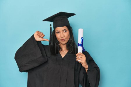 Foto de Filipina graduado con diploma en estudio azul se siente orgulloso y seguro de sí mismo, ejemplo a seguir. - Imagen libre de derechos
