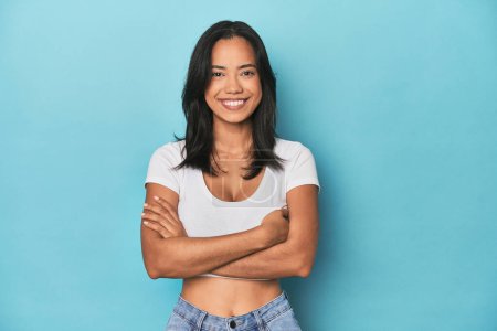 Photo for Filipina young woman on blue studio who feels confident, crossing arms with determination. - Royalty Free Image