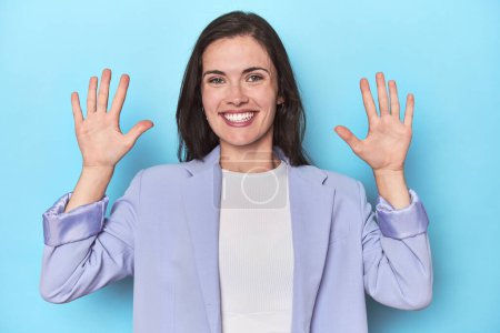 Photo for Woman in blue blazer on blue background showing number ten with hands. - Royalty Free Image