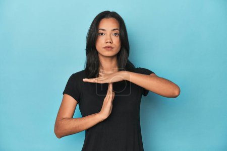 Photo for Filipina young woman on blue studio showing a timeout gesture. - Royalty Free Image