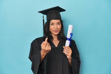 Foto de Filipina se gradúa con diploma en estudio azul señalándote con el dedo como si te invitara a acercarte. - Imagen libre de derechos