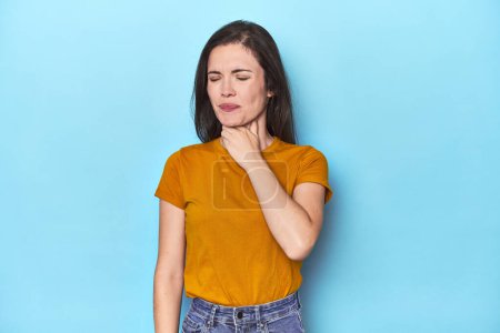 Photo for Young caucasian woman on blue backdrop suffers pain in throat due a virus or infection. - Royalty Free Image