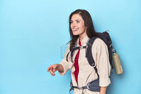 Téléchargez les photos : Femme aventureuse avec sac à dos et tapis sur bleu - en image libre de droit