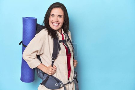 Photo for Adventurous woman with backpack and mat on blue - Royalty Free Image