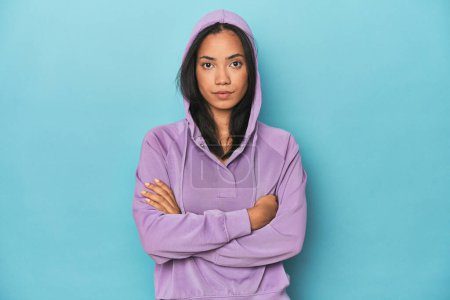 Photo for Filipina in purple sportswear hoodie on a blue studio background - Royalty Free Image