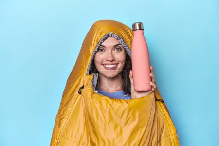 Photo for Young woman cozy inside camping sleeping bag showing a termo - Royalty Free Image