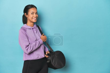 Foto de Joven Filipina con mochila deportiva para el gimnasio sobre fondo azul - Imagen libre de derechos
