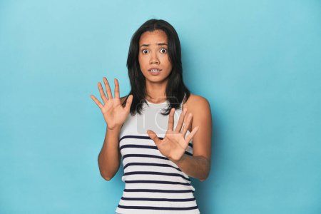 Photo for Filipina young woman on blue studio being shocked due to an imminent danger - Royalty Free Image