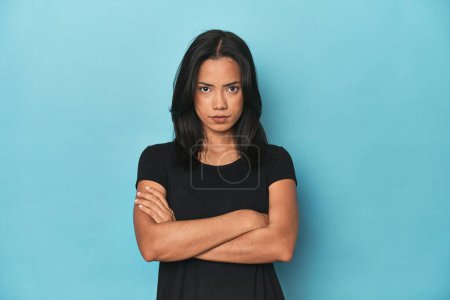Téléchargez les photos : Philippine jeune femme sur bleu studio fronçant les sourcils visage dans le mécontentement, garde les bras croisés. - en image libre de droit