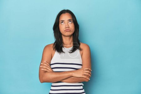 Photo for Filipina young woman on blue studio tired of a repetitive task. - Royalty Free Image