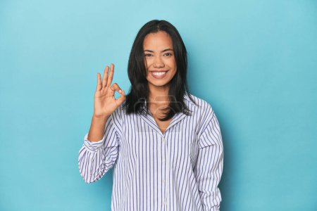 Photo for Filipina young woman on blue studio cheerful and confident showing ok gesture. - Royalty Free Image