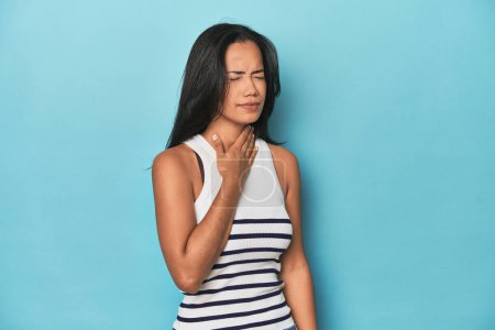 Foto de Filipina mujer joven en el estudio azul sufre dolor de garganta debido a un virus o infección. - Imagen libre de derechos