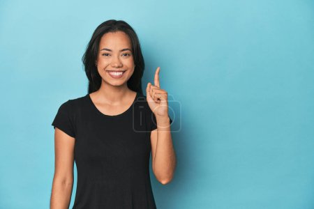 Foto de Filipina joven en estudio azul mostrando el número uno con el dedo. - Imagen libre de derechos