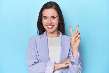 Téléchargez les photos : Femme en blazer bleu sur fond bleu montrant numéro deux avec les doigts. - en image libre de droit