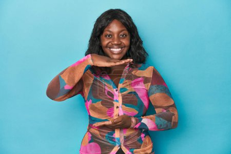 Foto de Mujer con curvas afroamericana joven sosteniendo algo con ambas manos, presentación del producto. - Imagen libre de derechos