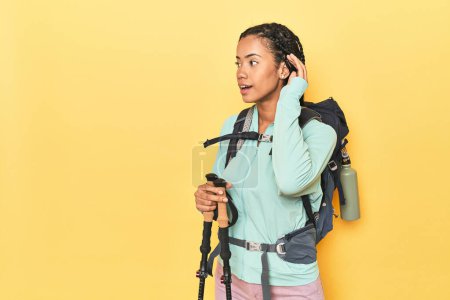 Foto de Mujer indonesia con equipo de senderismo en amarillo tratando de escuchar un chisme. - Imagen libre de derechos
