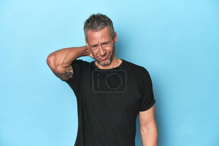 Photo for Middle-aged caucasian man on blue backdrop suffering neck pain due to sedentary lifestyle. - Royalty Free Image
