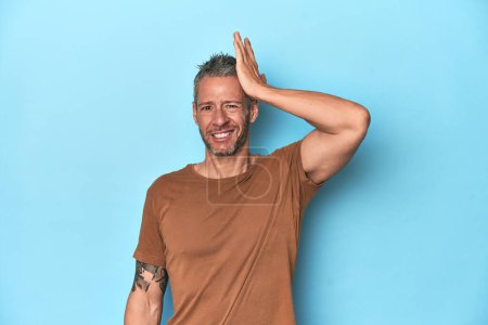 Photo for Middle-aged caucasian man on blue backdrop forgetting something, slapping forehead with palm and closing eyes. - Royalty Free Image