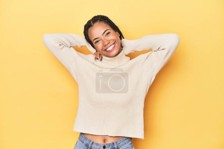 Photo for Young Indonesian woman on yellow studio backdrop stretching arms, relaxed position. - Royalty Free Image