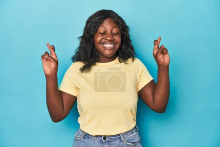 Téléchargez les photos : Jeune femme courbée afro-américaine croisant les doigts pour avoir de la chance - en image libre de droit