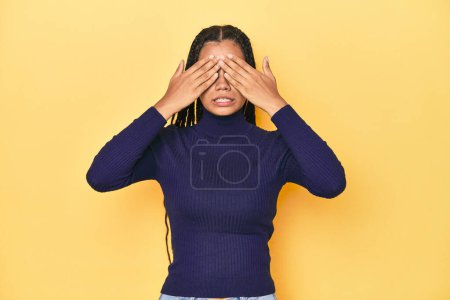 Photo for Young Indonesian woman on yellow studio backdrop afraid covering eyes with hands. - Royalty Free Image