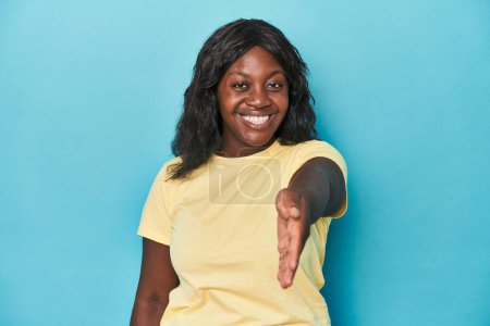 Foto de Joven africana americana curvilínea mujer estirando la mano a la cámara en gesto de saludo. - Imagen libre de derechos