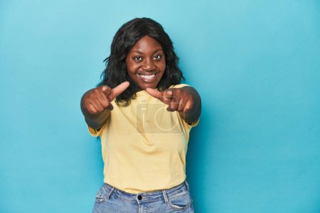 Téléchargez les photos : Jeune femme afro-américaine courbée sourire joyeux pointant vers l'avant. - en image libre de droit