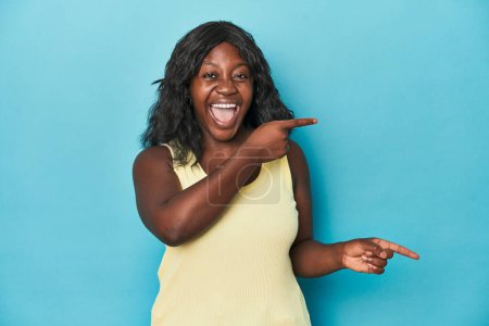 Téléchargez les photos : Jeune femme courbée afro-américaine pointant des index vers un espace de copie, exprimant excitation et désir. - en image libre de droit