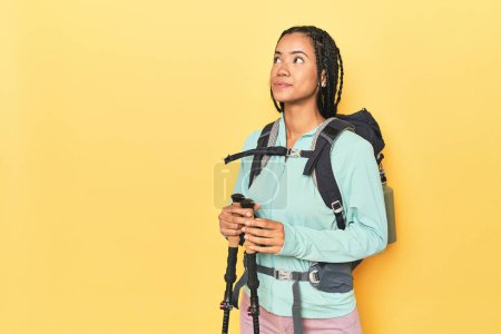 Téléchargez les photos : Femme indonésienne avec équipement de randonnée sur jaune rêvant d'atteindre des objectifs et des buts - en image libre de droit