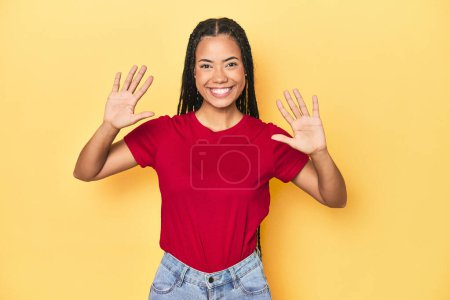 Photo for Young Indonesian woman on yellow studio backdrop showing number ten with hands. - Royalty Free Image