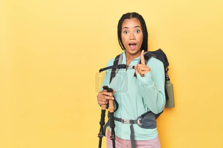Téléchargez les photos : Femme indonésienne avec équipement de randonnée sur jaune ayant une idée, concept d'inspiration. - en image libre de droit