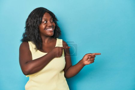Téléchargez les photos : Jeune femme afro-américaine courbée excitée pointant les index loin. - en image libre de droit