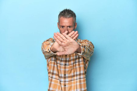 Photo for Middle-aged caucasian man on blue backdrop doing a denial gesture - Royalty Free Image