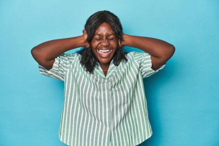 Téléchargez les photos : Jeune femme afro-américaine courbée couvrant les oreilles avec des mains essayant de ne pas entendre un son trop fort. - en image libre de droit