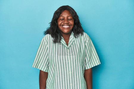 Foto de Joven africana americana curvilínea mujer se ríe y cierra los ojos, se siente relajado y feliz. - Imagen libre de derechos