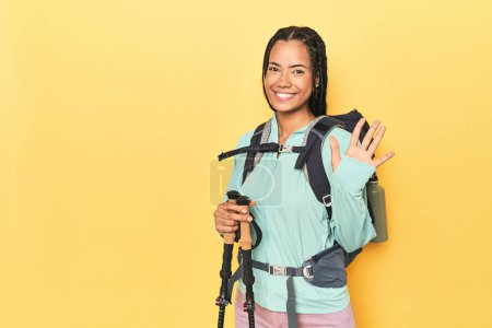 Foto de Mujer indonesia con equipo de senderismo en amarillo sonriente alegre mostrando el número cinco con los dedos. - Imagen libre de derechos