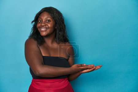 Foto de Joven mujer con curvas afroamericana sosteniendo un espacio de copia en una palma. - Imagen libre de derechos