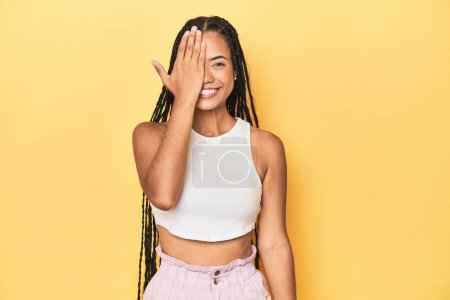 Photo for Young Indonesian woman on yellow studio backdrop having fun covering half of face with palm. - Royalty Free Image
