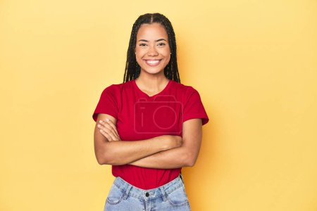 Photo for Young Indonesian woman on yellow studio backdrop who feels confident, crossing arms with determination. - Royalty Free Image