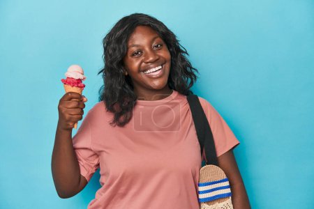 Foto de Joven mujer con curvas disfrutando de helado sobre un fondo azul - Imagen libre de derechos