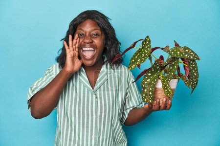 Téléchargez les photos : Jardinier courbé tenant plante en studio criant et tenant la paume près de l'ouverture de la bouche. - en image libre de droit