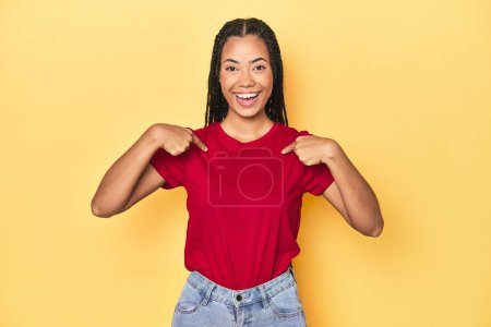 Photo for Young Indonesian woman on yellow studio backdrop surprised pointing with finger, smiling broadly. - Royalty Free Image