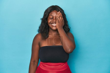 Téléchargez les photos : Jeune femme courbée afro-américaine s'amusant à couvrir la moitié du visage avec la paume. - en image libre de droit