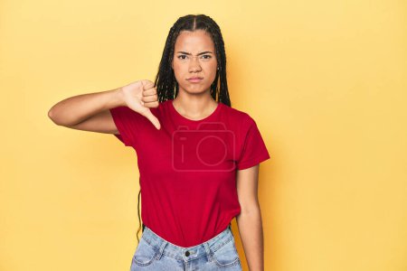 Photo for Young Indonesian woman on yellow studio backdrop showing thumb down, disappointment concept. - Royalty Free Image