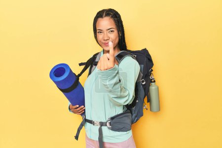 Foto de Mujer indonesia listo para el viaje de montaña en amarillo señalando con el dedo en usted como si invitando a acercarse. - Imagen libre de derechos