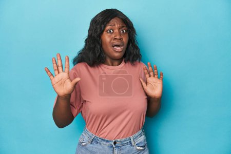 Photo for Young african american curvy woman being shocked due to an imminent danger - Royalty Free Image