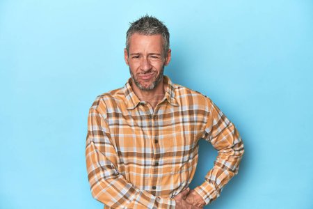 Photo for Middle-aged caucasian man on blue backdrop having a liver pain, stomach ache. - Royalty Free Image